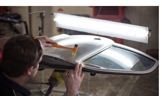 Technician performing paintless dent repair on a car roof